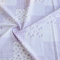 Découvrez le tissu popeline de coton style patchwork au mètre de Longan Craft France : motifs fleurs et carreaux pastel, parfait pour des vêtements stylés. Textile confortable, légèrement froissé, avec motifs variés en nuances violettes et blanches.
