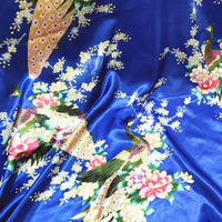Le Tissu satin imprimé paon au mètre de Longan Craft France présente des motifs colorés de paons, fleurs roses et blanches, et feuilles vertes. Sa texture satinée est idéale pour réaliser des accessoires élégants ou une décoration intérieure raffinée.