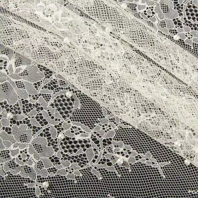 Gros plan sur la Dentelle perlée au mètre de Longan Craft France, un tissu de dentelle perlée de haute qualité pour le bricolage nuptial, présentant des motifs floraux et de petites perles dans des bandes horizontales qui se chevauchent sur un fond sombre.