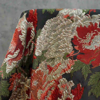 Gros plan sur le luxueux brocart Longan Craft France jacquard floral noir et doré, présentant des motifs de pivoines gaufrées en noir et or métallisés, idéal pour les robes de soirée. Tissu brocart métallisé vendu au mètre.