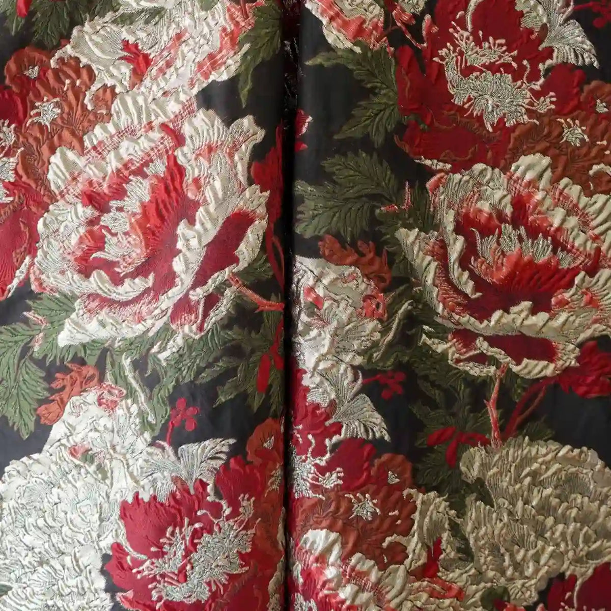 Gros plan sur le Tissu brocart métallisé embossé pivoine de Longan Craft France, un luxueux jacquard aux motifs floraux ornés de noir et d'or, parfait pour les robes du soir, à l'aspect texturé et métallique.