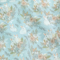 Le tissu lapin de Pâques rose et bleu au mètre 100% coton de Longan Craft France présente des motifs de lapins blancs, roses beige, feuillage vert et détails botaniques sur fond bleu clair à pois. Idéal pour projets DIY de saison.