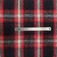 Une règle métallique de 0 à 15 cm est posée sur l'épaisse flanelle à carreaux de Longan Craft France, un plaid confortable en polyester-coton vendu au mètre, parfait pour la couture d'automne. Le tissu présente des rayures rouges, noires et blanches qui s'entrecroisent.