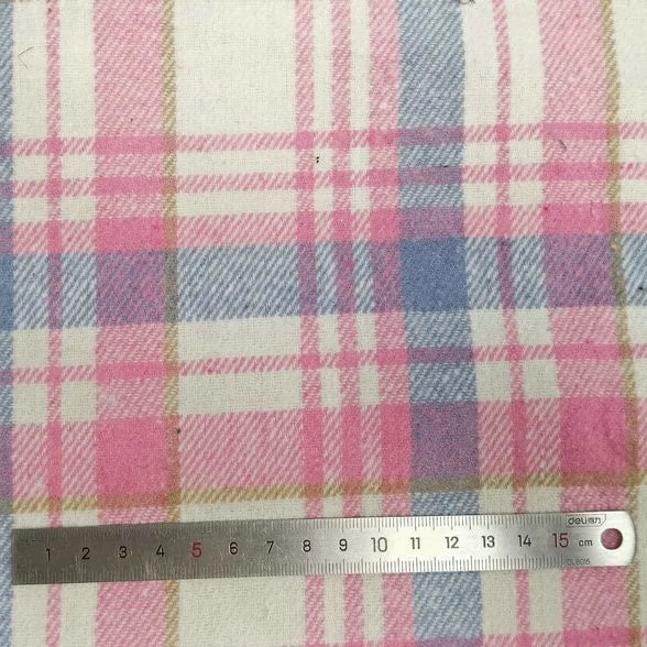 Gros plan sur le tissu flanelle épaisse brossée un côté à carreaux au mètre de Longan Craft France en rose, bleu et beige, avec une règle en métal de 15 cm pour l'échelle. Flanelle colorée en polyester-coton, parfaite pour les projets d'automne.