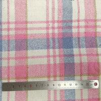 Gros plan sur le tissu flanelle épaisse brossée un côté à carreaux au mètre de Longan Craft France en rose, bleu et beige, avec une règle en métal de 15 cm pour l'échelle. Flanelle colorée en polyester-coton, parfaite pour les projets d'automne.