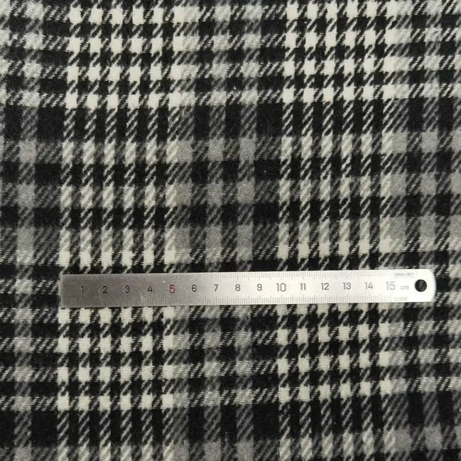 Une règle en métal de 15 cm repose sur le Tissu flanelle épaisse brossée un côté à carreaux de Longan Craft France, un tissu à carreaux confortable en polyester et coton, parfait pour l'automne.