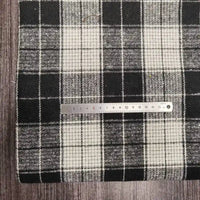Une règle métallique de 1 à 15 cm est posée sur l'épaisse flanelle à carreaux (polyester-coton) de Longan Craft France, parfaite pour l'automne, le tissu reposant sur une surface en bois sombre.
