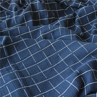 Gros plan sur le Tissu double gaze de coton à carreaux marine de Longan Craft France, montrant son motif quadrillé blanc, sa texture douce et ses plis délicats. Il s'agit d'un tissu respirant et confortable vendu au mètre.