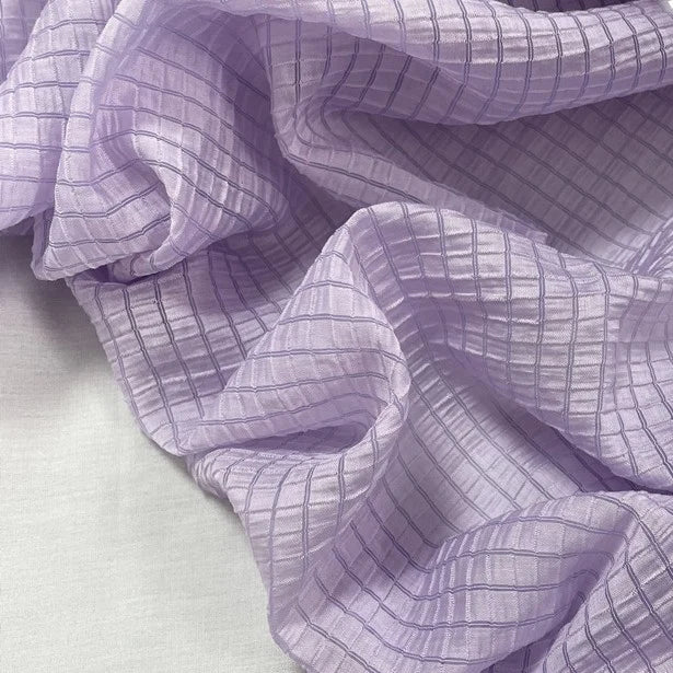 Gros plan sur le jacquard Tissu lyocell à carreaux au mètre de Longan Craft France, de couleur violet clair avec un motif quadrillé. Ce textile léger, respirant et semi-transparent est parfait pour les vêtements élégants.