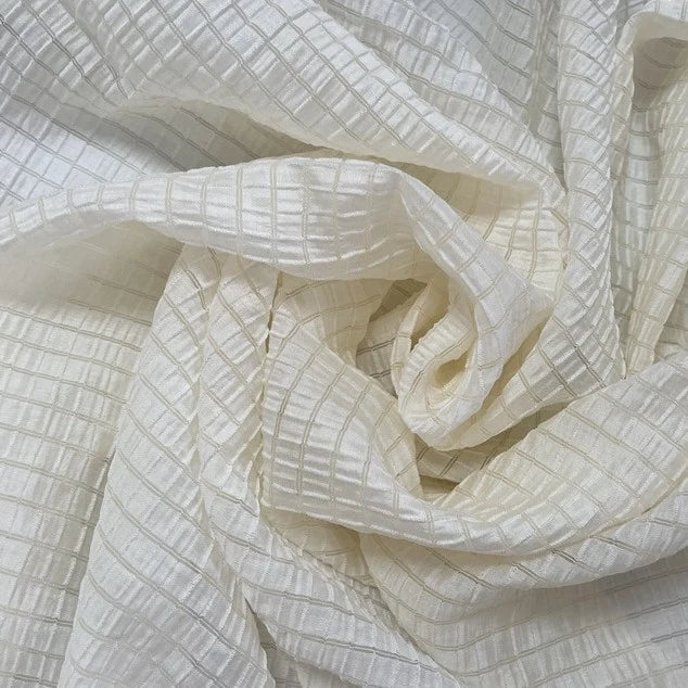 Un gros plan du tissu lyocell jacquard à carreaux au mètre de Longan Craft France montre sa texture quadrillée, semi-transparente, avec des plis subtils. Ce textile multicolore respirant est idéal pour l'habillement.