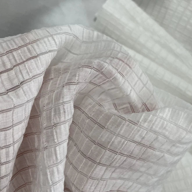 Gros plan sur le Tissu lyocell jacquard à carreaux au mètre de Longan Craft France - un textile léger et respirant avec un motif de grille semi-transparent et des plis doux, parfaits pour créer des vêtements élégants.