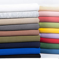 Une pile de Tissu French terry uni au mètre de Longan Craft France en couleurs assorties - le tissu polyester idéal pour les vêtements d'hiver et les sweatshirts.