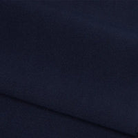 Gros plan sur le pliage de Longan Craft France Tissu French terry uni au mètre - polyester bleu marine foncé à la texture lisse et mate et au tissage fin. Ce tissu doux est idéal pour les vêtements d'hiver et est bien rangé sur l'image.