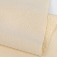 Gros plan sur le Tissu French terry uni au mètre de Longan Craft France en beige clair, mettant en évidence le recto lisse et le verso texturé de ce tissu polyester doux, idéal pour les vêtements d'hiver, dont la trame et les bords sont clairement visibles.