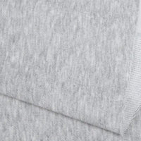 Un gros plan du Tissu French terry uni au mètre de Longan Craft France montre deux pièces gris clair qui se chevauchent, avec une surface lisse et subtilement texturée et un bord légèrement plié - un tissu polyester doux parfait pour les vêtements d'hiver.