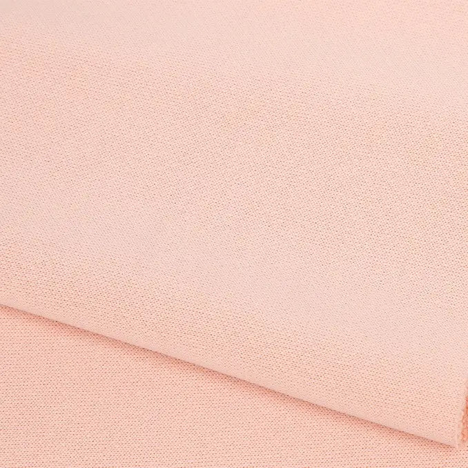 Gros plan sur le doux tissu French terry uni au mètre de Longan Craft France en polyester rose pâle, soigneusement plié pour mettre en valeur sa texture fine - idéal pour les vêtements d'hiver et les sweatshirts élégants.