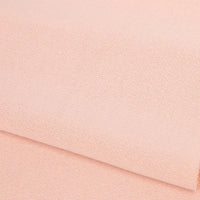 Gros plan sur le doux tissu French terry uni au mètre de Longan Craft France en polyester rose pâle, soigneusement plié pour mettre en valeur sa texture fine - idéal pour les vêtements d'hiver et les sweatshirts élégants.