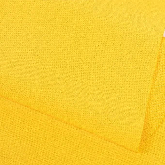 Un gros plan de Tissu French terry uni au mètre de Longan Craft France montre un tissu en polyester doux, jaune vif, au tissage subtil. Les pièces superposées dans une lumière uniforme mettent en valeur la texture de la matière, idéale pour les vêtements d'hiver confortables.