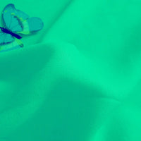 Un pli visible apparaît sur le Tissu jersey viscose uni au mètre de Longan Craft France, avec un papillon bleu en haut à gauche. Le filtre verdâtre met en évidence la douceur de la viscose 100% rayonne, idéale pour la confection de robes.