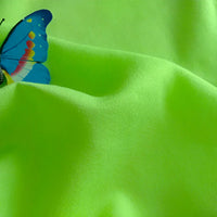 Un papillon bleu avec des taches orange repose sur un vert vif Longan Craft France Tissu jersey viscose uni au mètre, 100% rayonne viscose-un tissu parfait pour les robes.