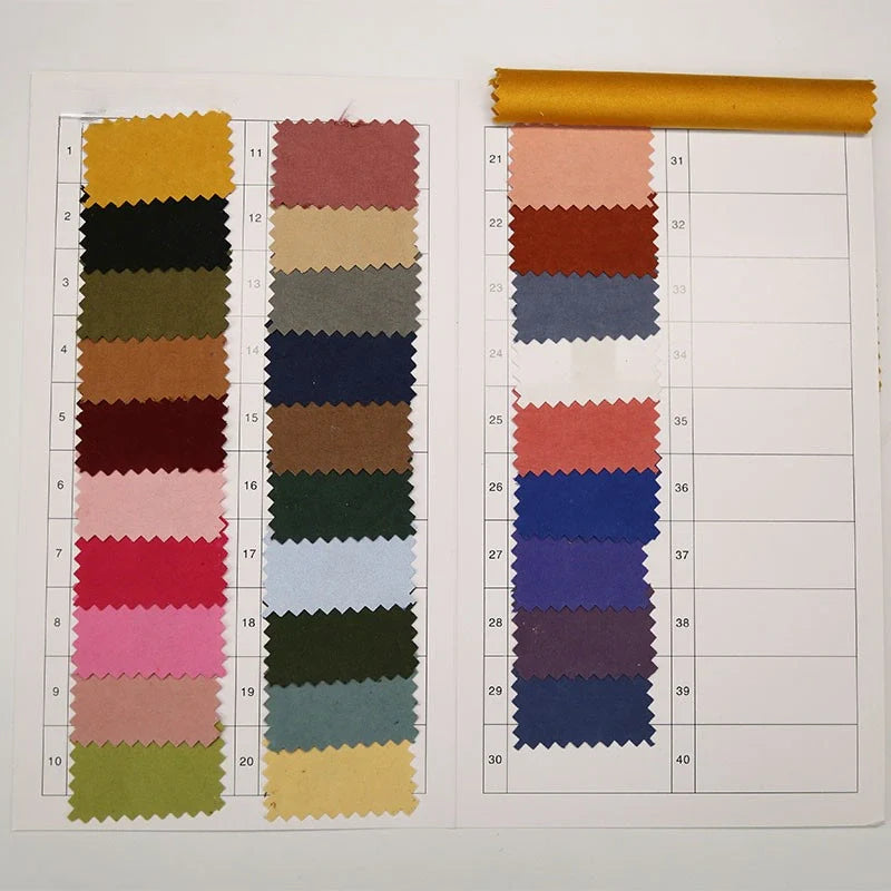 Un nuancier pour le microsuède polyester multicolore au mètre, texture peau de pêche brossée, de Longan Craft France, présente 30 échantillons de tissu aux bords rosés sur deux feuilles, plus des espaces vierges et un échantillon jaune en haut à droite.