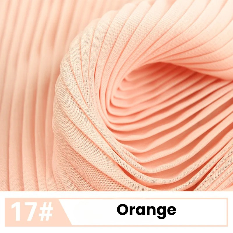 Gros plan sur la Mousseline plissée unie de Longan Craft France, de couleur orange clair, élégamment tourbillonnée. L'étiquette du bas indique "17# Orange". Tissu léger idéal pour les robes et les chemisiers chics.