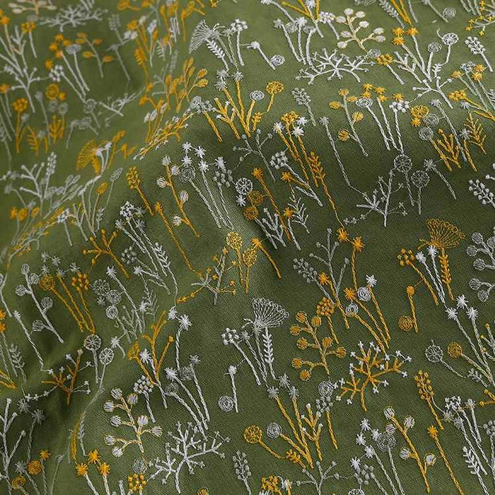 Longan Craft France présente le Tissu brodé de motifs végétaux au mètre : une étoffe verte ornée de fleurs et plantes jaunes et blanches, à surface texturée, parfaite pour vêtements, accessoires ou décoration d'inspiration nature.