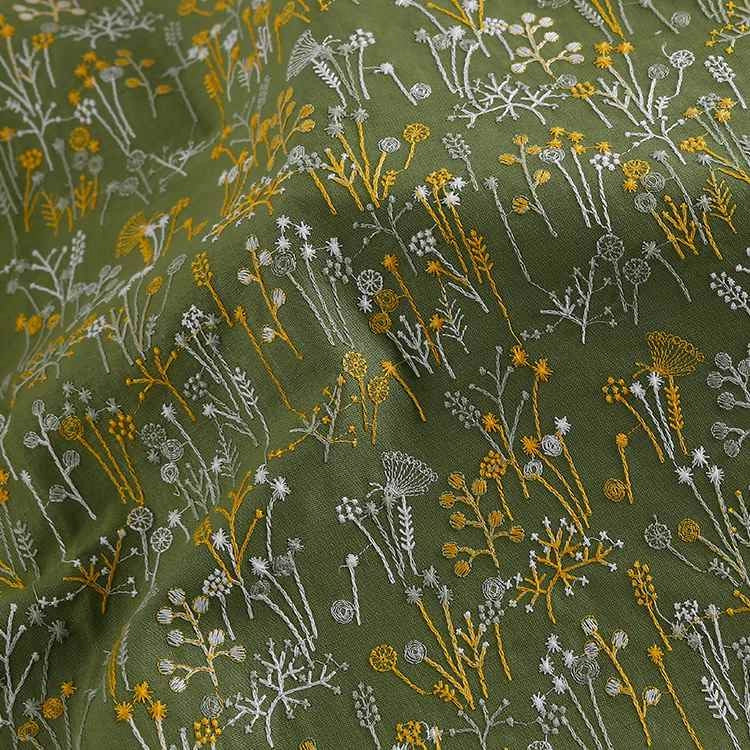 Longan Craft France présente le Tissu brodé de motifs végétaux au mètre : une étoffe verte ornée de fleurs et plantes jaunes et blanches, à surface texturée, parfaite pour vêtements, accessoires ou décoration d'inspiration nature.