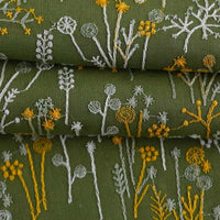 Le Tissu brodé de motifs végétaux au mètre de Longan Craft France, vert avec des motifs blancs et jaunes, est idéal pour vêtements, accessoires ou décoration grâce à ses délicates fleurs et tiges répétées.