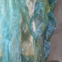 Gros plan sur Tissu organza irisé plissé au mètre de Longan Craft France : panneaux semi-transparents, bicolores à dégradé en bleu pâle et vert, superposés verticalement avec des effets de lumière chatoyants et fluides.