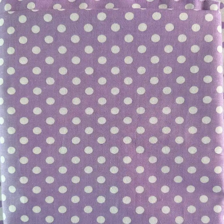 Gros plan sur le Tissu patchwork en coton imprimé pois au mètre de Longan Craft France, montrant un fond violet clair avec des points blancs régulièrement espacés - tissu idéal pour le quilting et les vêtements, légèrement plié sur le bord supérieur.