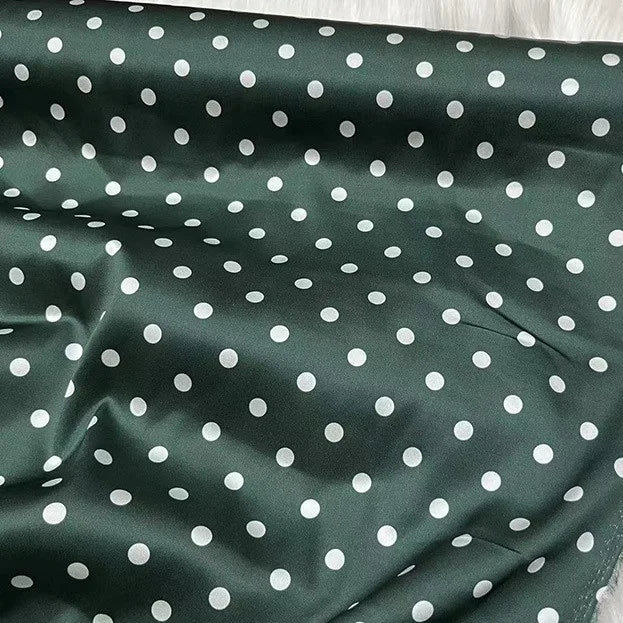 Un tissu de soie extensible vert foncé d'inspiration vintage de Longan Craft France, 19 momme soie imprimée à pois blancs, apparaît légèrement froissé et présenté à plat ; idéal pour l'habillement.