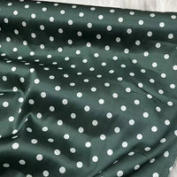 Un tissu de soie extensible vert foncé d'inspiration vintage de Longan Craft France, 19 momme soie imprimée à pois blancs, apparaît légèrement froissé et présenté à plat ; idéal pour l'habillement.