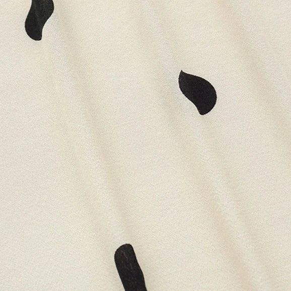 Gros plan sur le Tissu viscose fleuri à pois au mètre de Longan Craft France, 100 % viscose avec une surface légère et texturée et des pois noirs épars - un tissu tendance parfait pour confectionner des jupes longues.