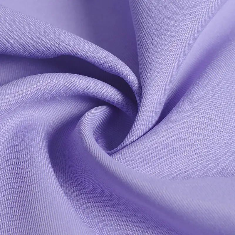 Gros plan sur le tissu gabardine violet clair 100 % polyester au mètre de Longan Craft France, avec une texture sergé uni lisse et un tissage diagonal fin - idéal pour les gilets élégants ou les uniformes.
