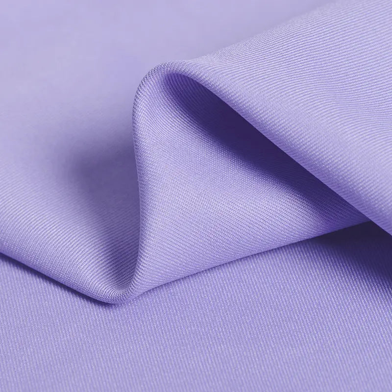 Un gros plan du Tissu gabardine 100 % polyester au mètre de Longan Craft France montre son tissage sergé lilas et ses plis doux - une qualité idéale pour créer des tissus de veste élégants.