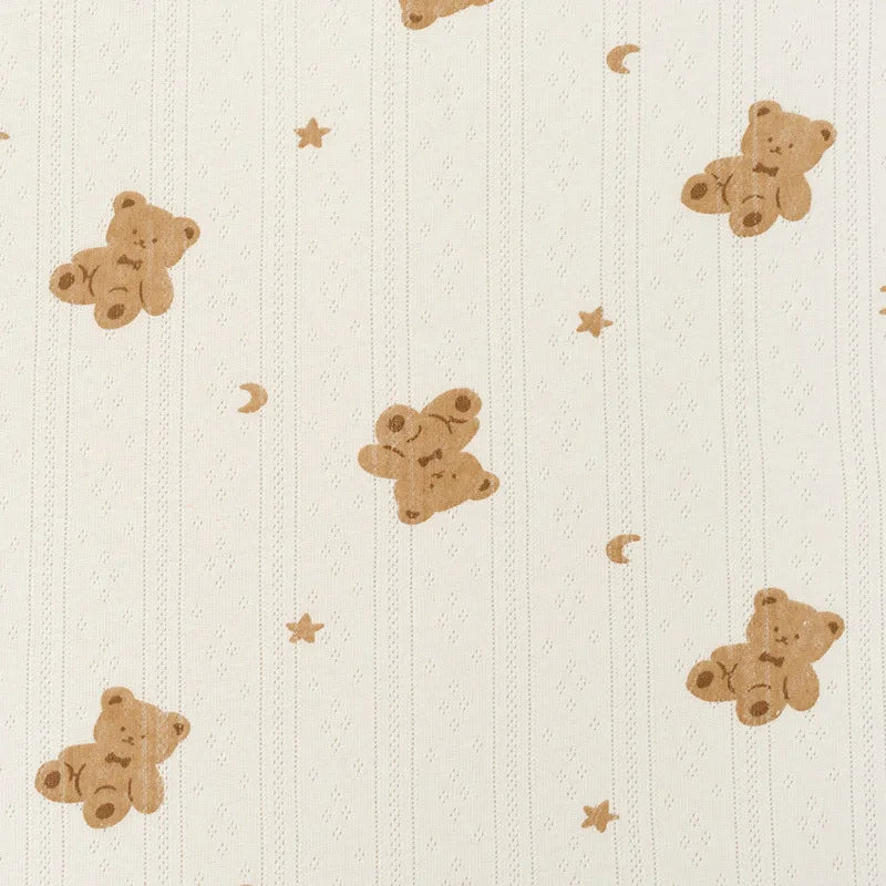 Le Tissu pointelle en coton imprimé au mètre de Longan Craft France offre un motif crème avec des oursons brun clair, étoiles et lunes, idéal pour la couture DIY de vêtements d'enfants grâce à sa maille douce et de haute qualité.