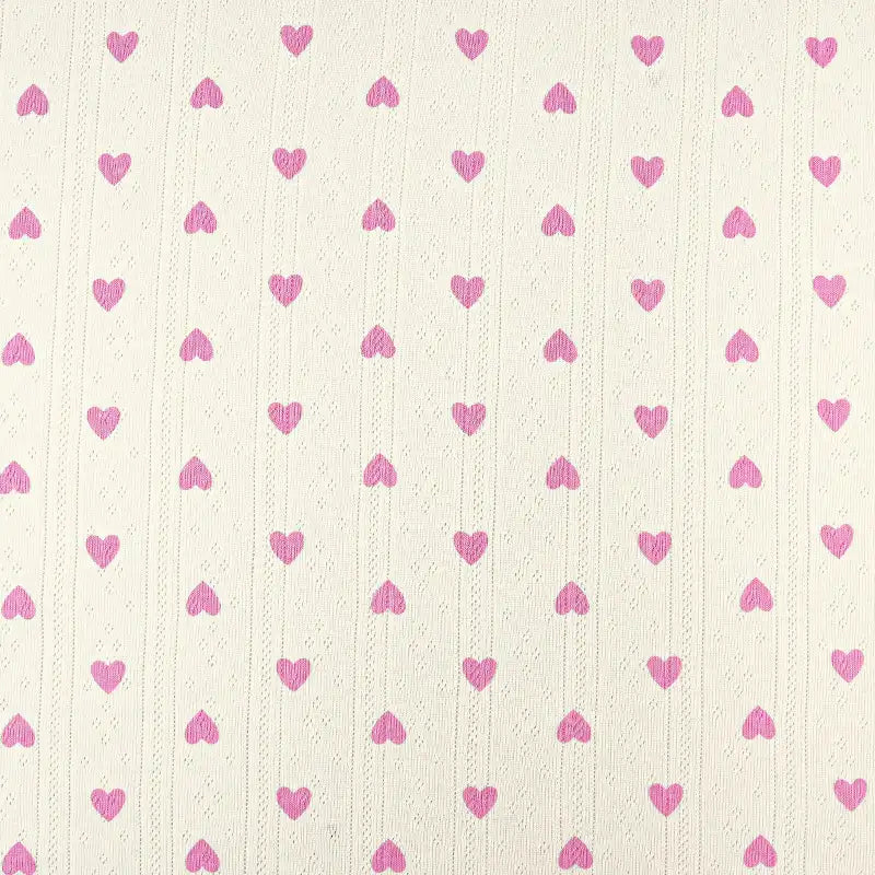 Un fond crème avec des lignes verticales de petits cœurs roses dans une grille - idéal pour les vêtements d'enfants DIY. Tissu pointelle en coton imprimé by Longan Craft France, tissu maille de qualité au mètre pour couture enfant.