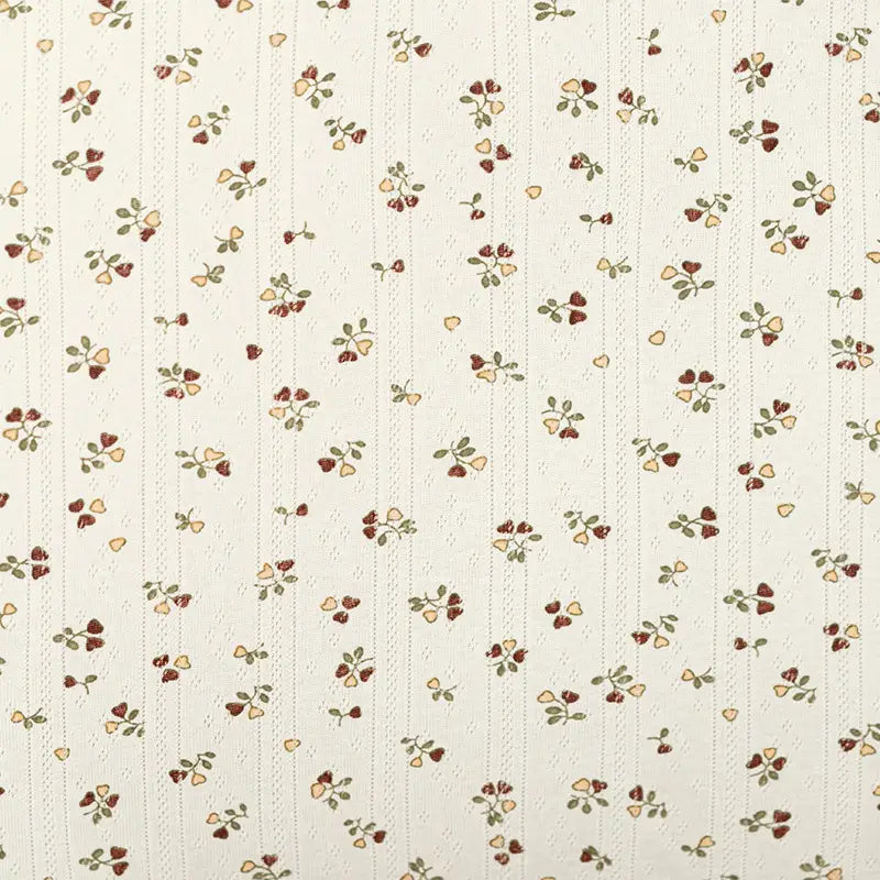 Tissu en coton pointelle crème de Longan Craft France, présentant de petits motifs floraux rouges, jaunes et verts en rangées verticales et de subtiles rayures en pointillés. Parfait pour le bricolage de vêtements pour enfants, avec une finition tricotée douce et de haute qualité.
