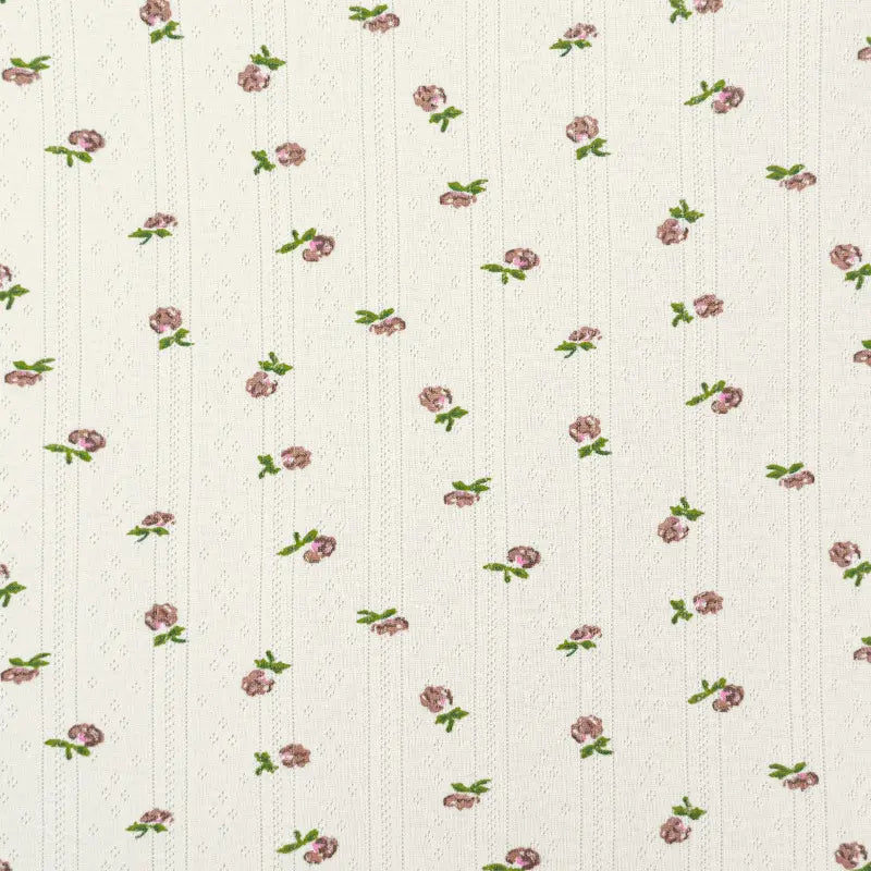 Le Tissu pointelle en coton imprimé au mètre de Longan Craft France est un tissu en coton de haute qualité de couleur crème avec une répétition de petites fleurs roses et de feuilles vertes, ainsi que de subtiles lignes verticales en pointillés - idéal pour les vêtements d'enfants DIY.