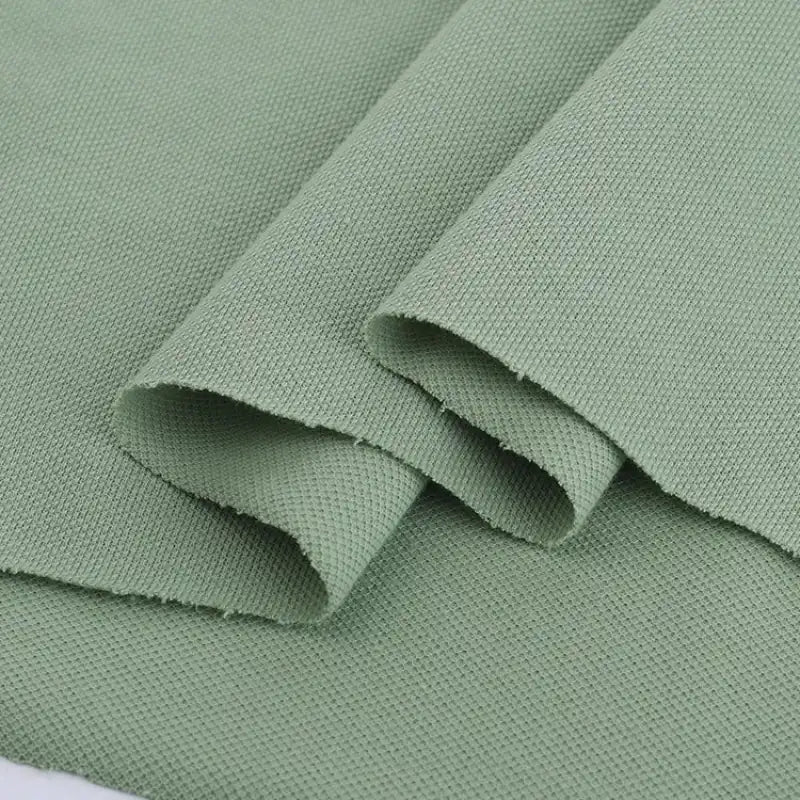 Gros plan sur le Piqué de coton uni au mètre de Longan Craft France - tissu jersey de coton vert clair à armure apparente, idéal pour la couture de bricolage et la confection de polos élégants.