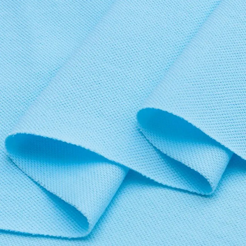 Gros plan sur le Piqué de coton uni au mètre bleu clair de Longan Craft France, un jersey lisse et légèrement extensible idéal pour les polos, les vêtements ou les projets de bricolage. Il présente un motif tissé et est plié en trois parties.