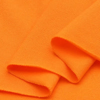 Gros plan sur le piqué de coton uni au mètre orange plié de Longan Craft France, montrant sa surface texturée et légèrement brillante en jersey tricoté, idéal pour les polos ou les projets de couture DIY.