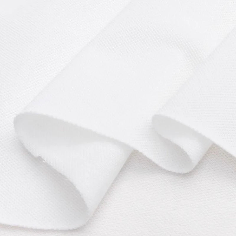 Gros plan sur le piqué de coton uni au mètre de Longan Craft France - un tissu piqué en jersey blanc lisse et uni, plié librement, parfait comme tissu pour chemises ou pour des projets de couture DIY.