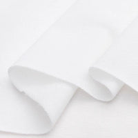 Gros plan sur le piqué de coton uni au mètre de Longan Craft France - un tissu piqué en jersey blanc lisse et uni, plié librement, parfait comme tissu pour chemises ou pour des projets de couture DIY.
