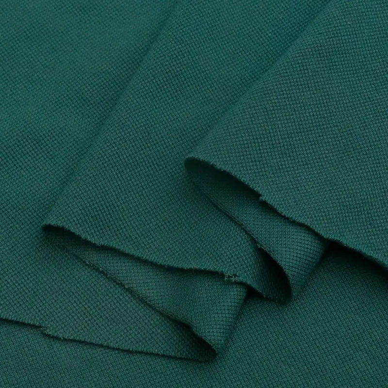 Gros plan sur le Piqué de coton uni au mètre vert foncé de Longan Craft France, montrant un tissage finement texturé et des bords bruts - tissu piqué idéal pour les polos ou les projets de couture DIY au mètre.