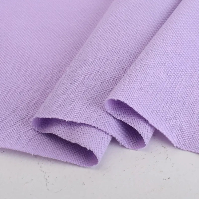 Gros plan sur le piqué de coton uni au mètre de Longan Craft France, un tissu de jersey tricoté violet clair soigneusement plié avec un motif tissé subtil - idéal pour les polos, les chemises et les projets de couture DIY.