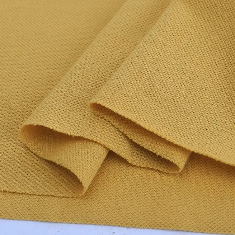Gros plan sur le Piqué de coton uni au mètre de Longan Craft France, soigneusement plié pour montrer sa texture - le tissu piqué de coton jersey idéal pour coudre des polos, des chemises et d'élégants projets de couture DIY.