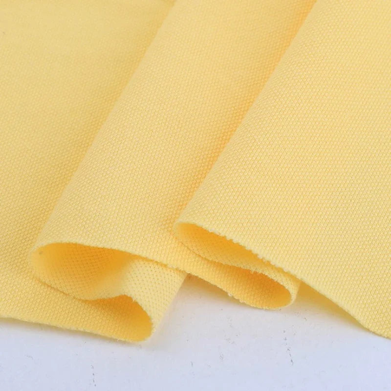 Gros plan sur deux pièces superposées de Piqué de coton uni au mètre jaune clair de Longan Craft France, montrant la surface texturée et tissée - parfait tissu piqué jersey pour polos et couture DIY.