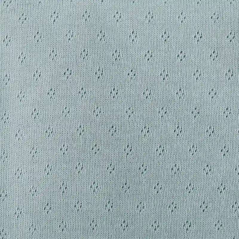 Tissu jersey pointelle 100 % coton au mètre de Longan Craft France, doux et léger avec motifs losanges. Parfait pour body bébé ou sous-vêtements DIY, il offre confort et touche décorative discrète grâce à son design jacquard.